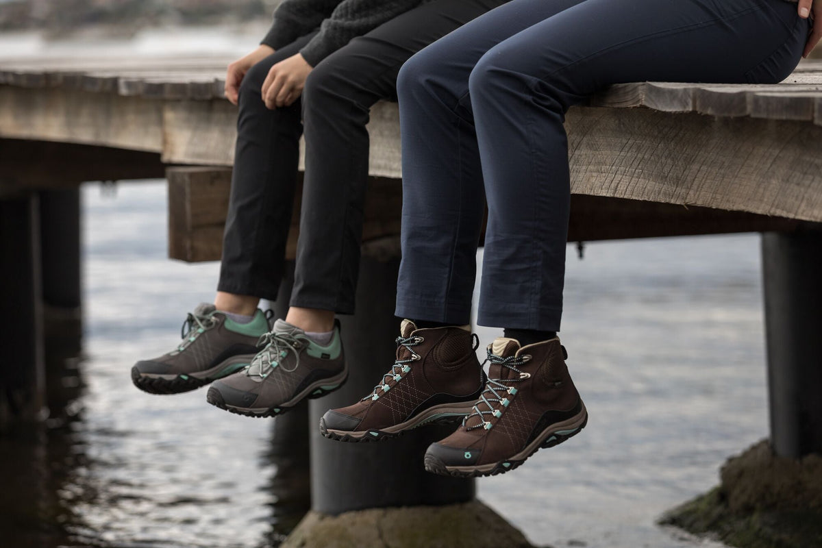 People sitting on a wharf wearing Oboz hiking boots
