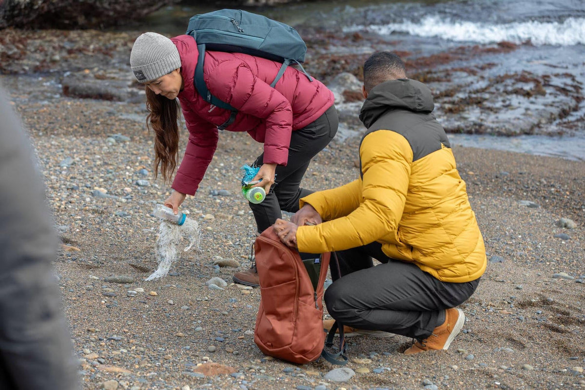 A couple picking up plastic at a beach to clean up.
