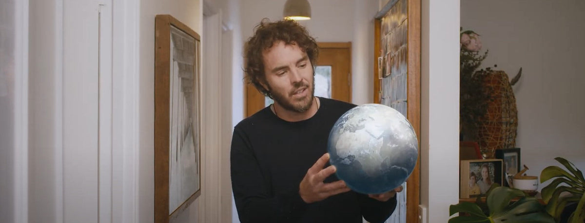 Damon Gemeau at his home holding planet earth in his hands.