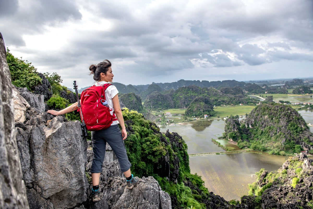 A female hiker out on a rocky trail overlooking the surrounding landscape.
